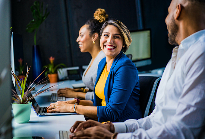 Happy woman typing on a laptop talking to other people